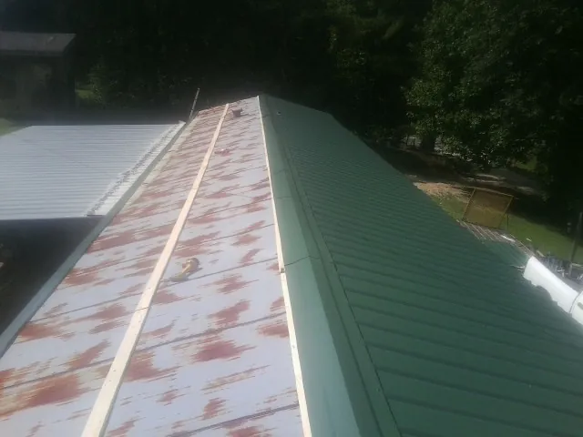 Old rusted panels beside newly installed green metal roofing — Wind Damage Roof Repair by Roofing Brothers in Sedalia